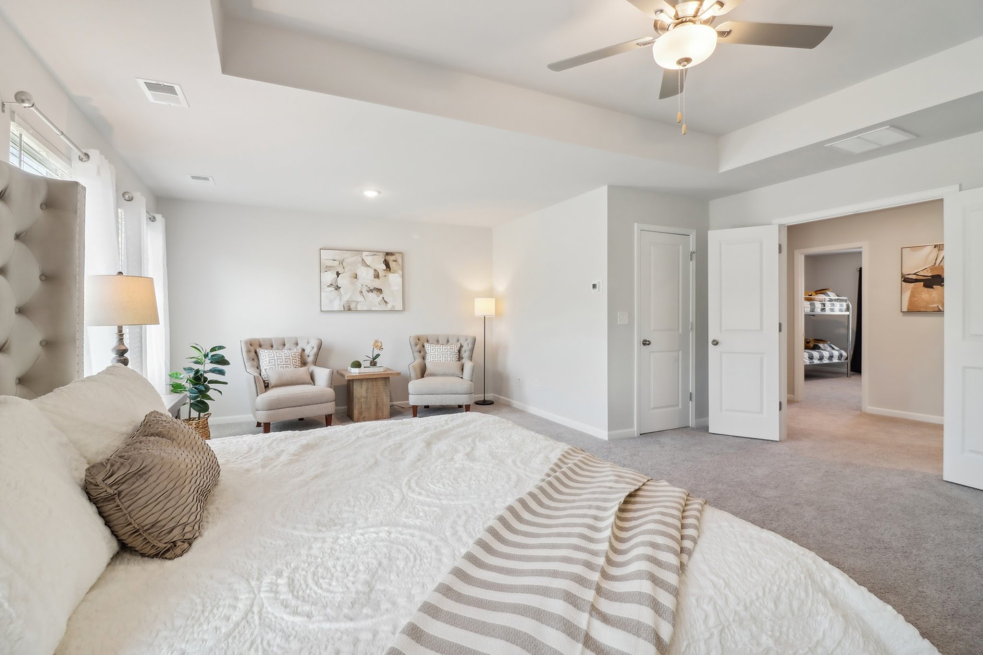 a bohemian style room with tray ceiling and a fan 