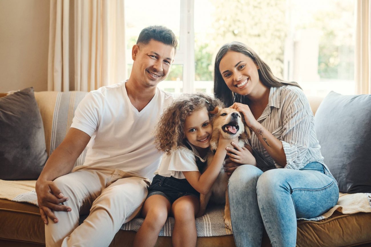 Family relaxing on the couch with their dog after buying a townhome for sale in Woodstock, GA