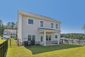 View of the back of a new home with an extended covered back patio and fenced-in backyard.