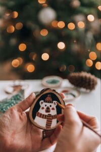 erson painting a polar bear on a DIY wooden Christmas ornament for a holiday craft project. ©Wirestock Creators