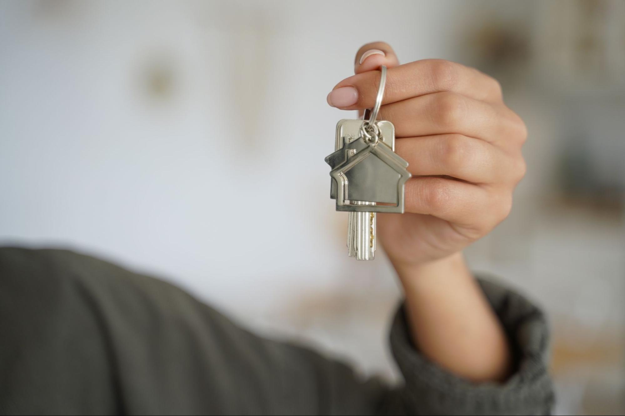 Person holding keys to their new home, symbolizing the move from renting to owning. ©StudioVK