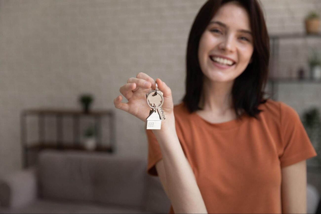 Smiling young woman holding keys to her new home, celebrating her move. ©fizkes