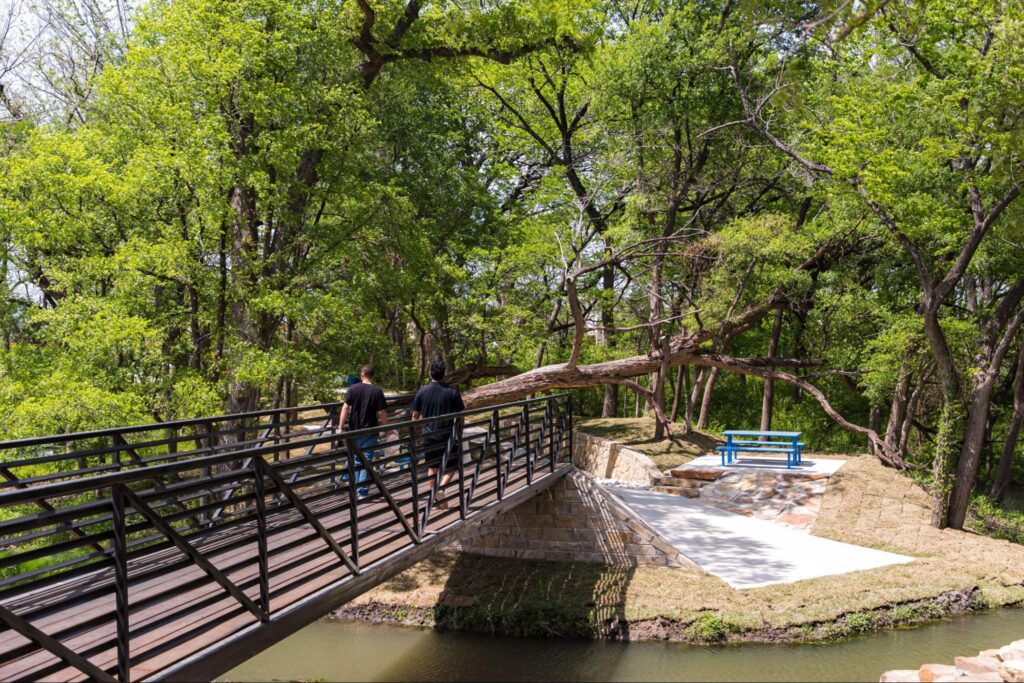 People walking across a bridge at Falling Tree Trail in Solterra Texas 