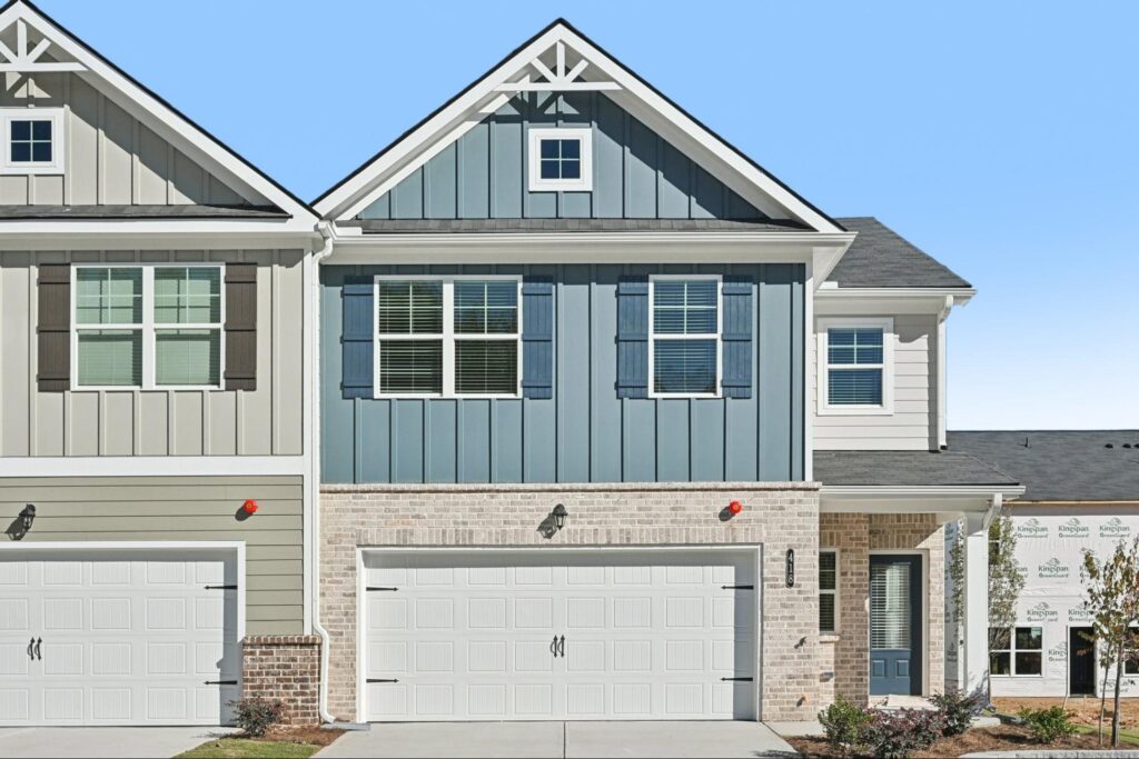 Modern townhome exterior at Chastain Heights featuring blue siding, white trim, and a two-car garage