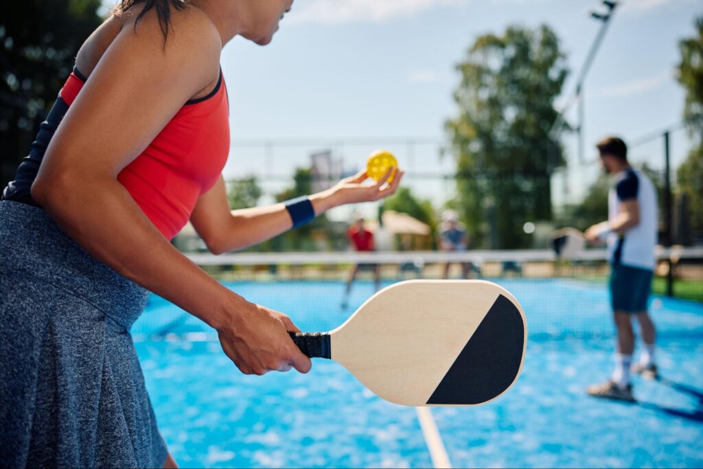 Woman serving during a pickleball match with friends
©Drazen Zigic