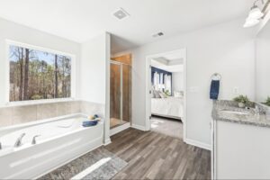 Luxurious primary bathroom with a soaking tub and walk-in shower in a new Winder home.