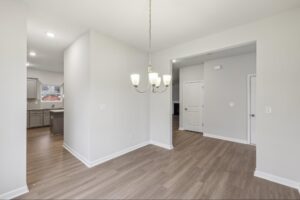 Formal dining room with modern chandelier lighting near the kitchen. 