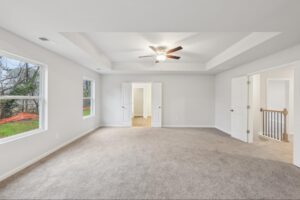 Expansive primary suite with private sitting area and ceiling fan. 