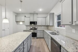 Modern kitchen with oversized granite island and grey cabinetry in Loganville, GA. 