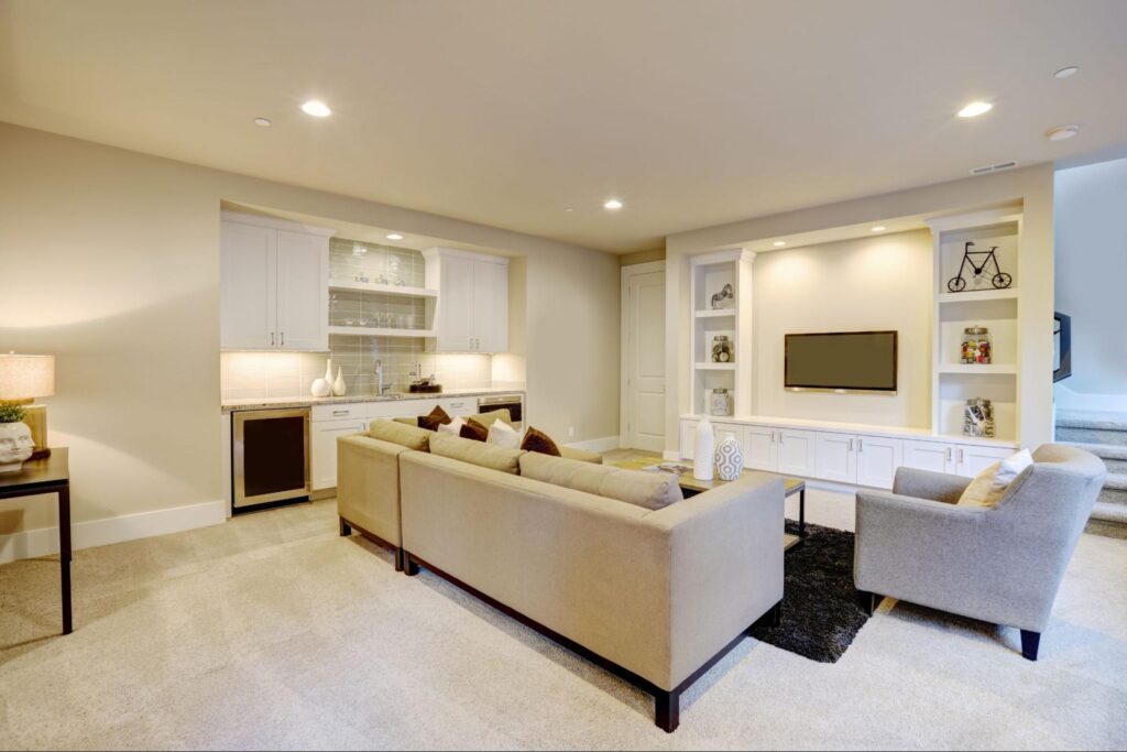 Modern finished basement media room featuring built-in shelving, TV, and comfortable seating.