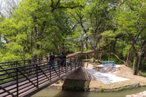 Residents walking across a pedestrian bridge on the hiking and biking nature trails at Solterra Texas.